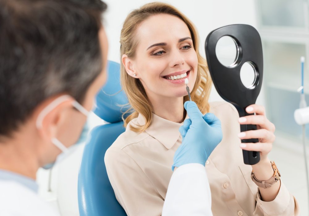 female-patient-choosing-tooth-implant-looking-at-mirror-in-modern-dental-clinic.jpg